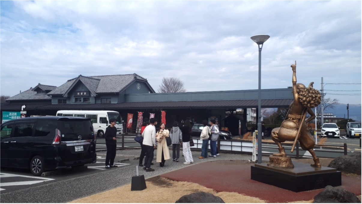 阿蘇駅ウソップ像の写真を撮る留学生