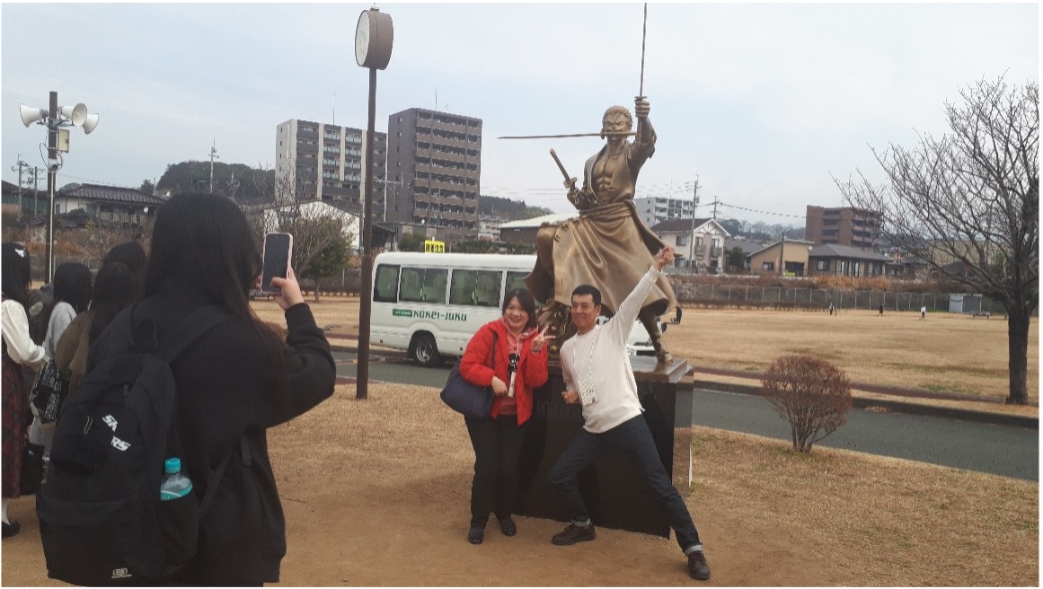 大津町ゾロ像前でポーズを取る新民高校の先生